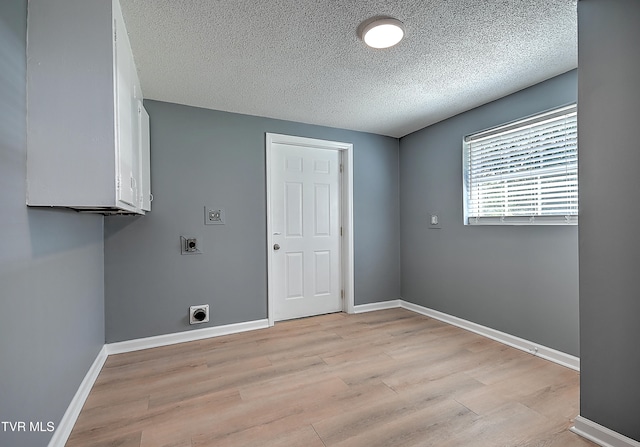 laundry area featuring cabinets, a textured ceiling, light wood-type flooring, and electric dryer hookup