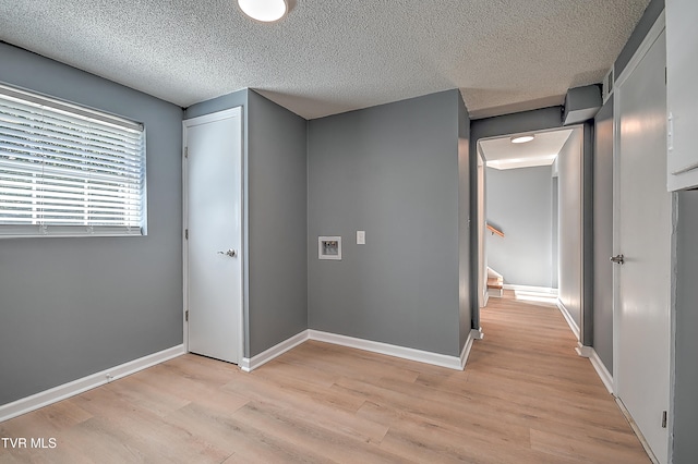 hall with a textured ceiling and light hardwood / wood-style floors