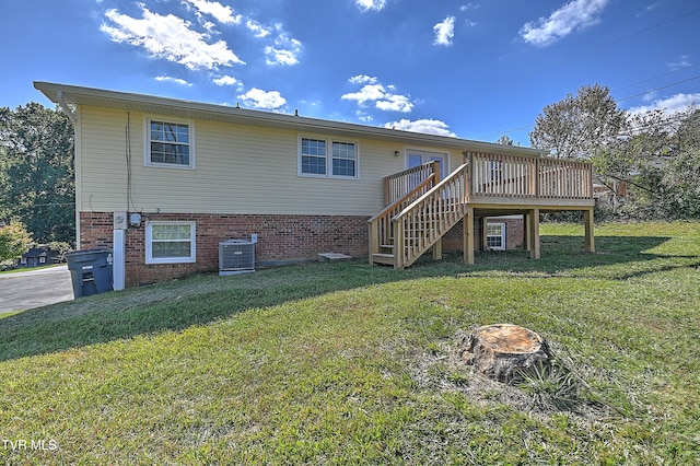 back of property with a deck, a lawn, and central air condition unit