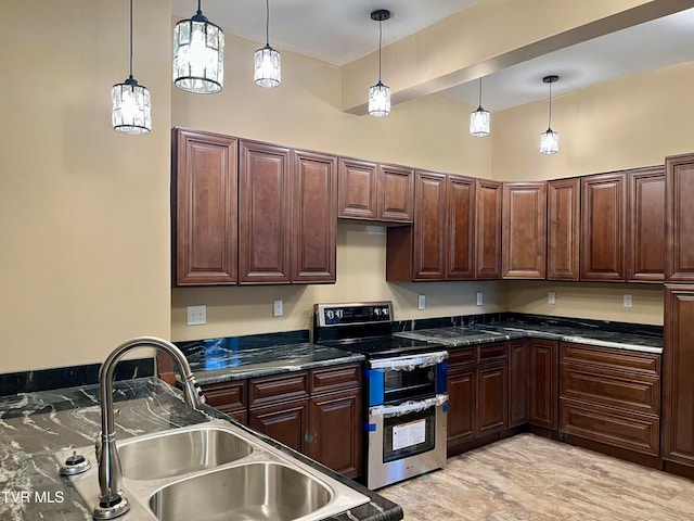 kitchen featuring dark brown cabinetry, decorative light fixtures, range with two ovens, dark stone counters, and sink