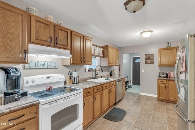 kitchen with sink, light tile patterned floors, a textured ceiling, light stone countertops, and appliances with stainless steel finishes