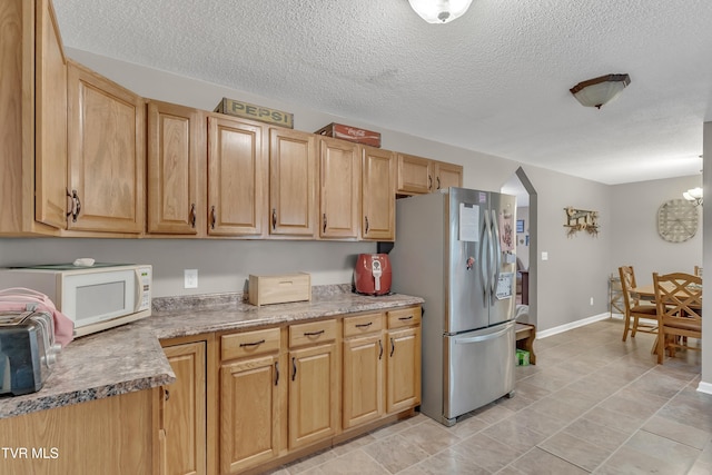 kitchen with stainless steel refrigerator, light tile patterned flooring, a chandelier, and a textured ceiling