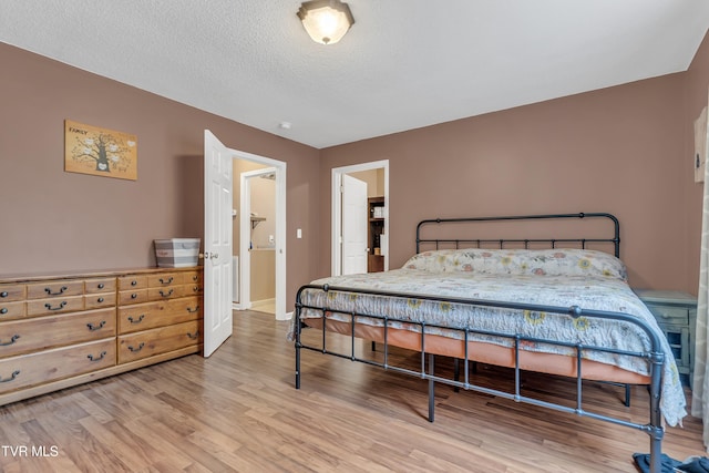 bedroom with a textured ceiling and light hardwood / wood-style flooring