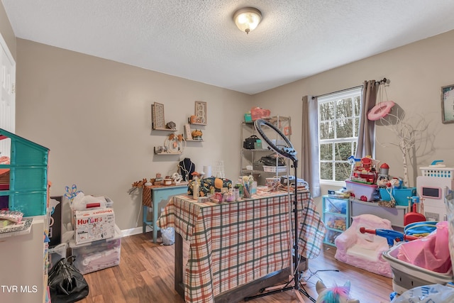 recreation room with hardwood / wood-style floors and a textured ceiling