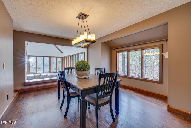 dining space featuring hardwood / wood-style floors, a notable chandelier, and a textured ceiling