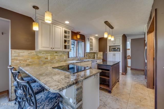 kitchen with kitchen peninsula, pendant lighting, a breakfast bar, and a textured ceiling