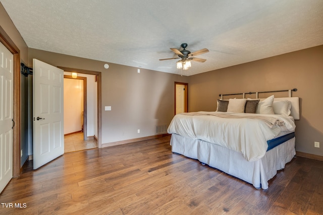 bedroom with ceiling fan, hardwood / wood-style floors, and a textured ceiling