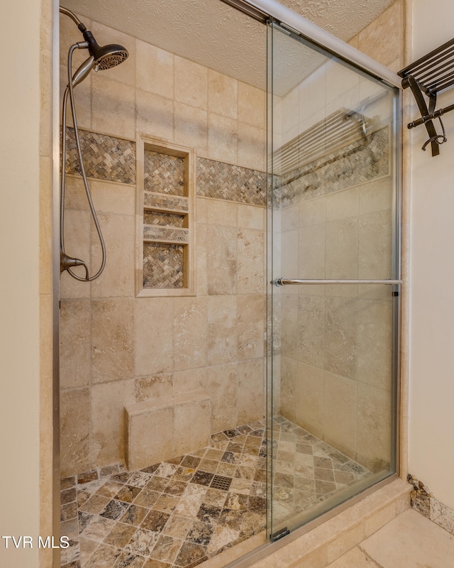 bathroom featuring a textured ceiling and a shower with door