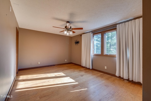 spare room featuring a textured ceiling, light wood-type flooring, and ceiling fan