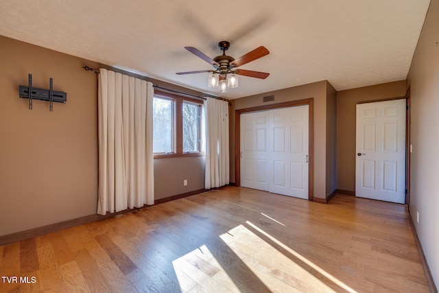 unfurnished bedroom featuring ceiling fan, a closet, a textured ceiling, and light hardwood / wood-style flooring