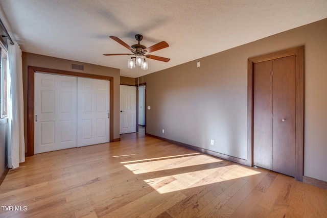 unfurnished bedroom with a textured ceiling, light wood-type flooring, and ceiling fan