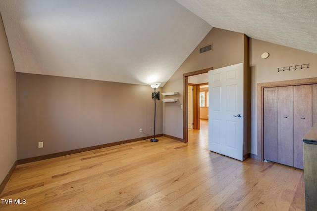 additional living space with light hardwood / wood-style flooring, high vaulted ceiling, and a textured ceiling