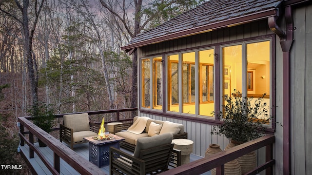 wooden deck with a sunroom and an outdoor living space with a fire pit