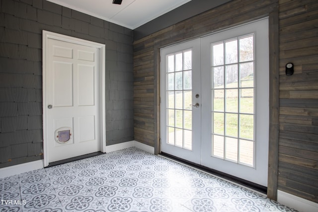 doorway with wood walls, french doors, and ornamental molding