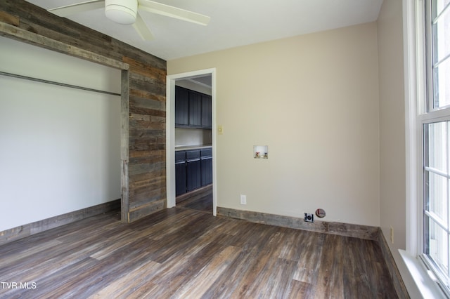 unfurnished bedroom with ceiling fan, wood walls, a closet, and multiple windows