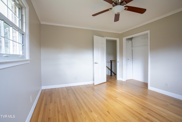 unfurnished bedroom with ceiling fan, light wood-type flooring, crown molding, and a closet