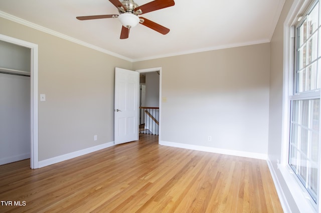 unfurnished bedroom featuring light wood-type flooring, multiple windows, and crown molding