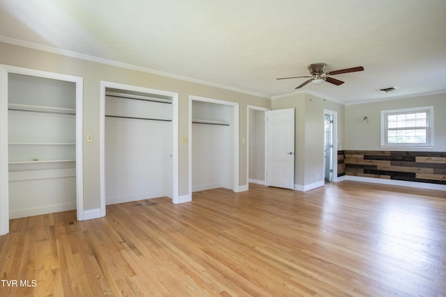 unfurnished bedroom with ceiling fan, light hardwood / wood-style floors, two closets, and ornamental molding