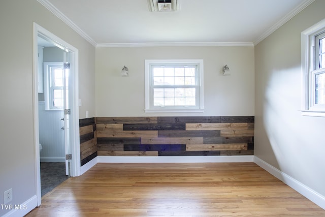 empty room featuring ornamental molding, light hardwood / wood-style flooring, and a healthy amount of sunlight