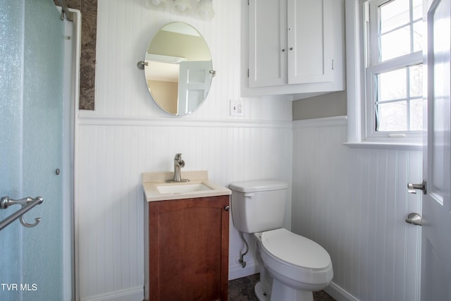 bathroom with wooden walls, vanity, and toilet