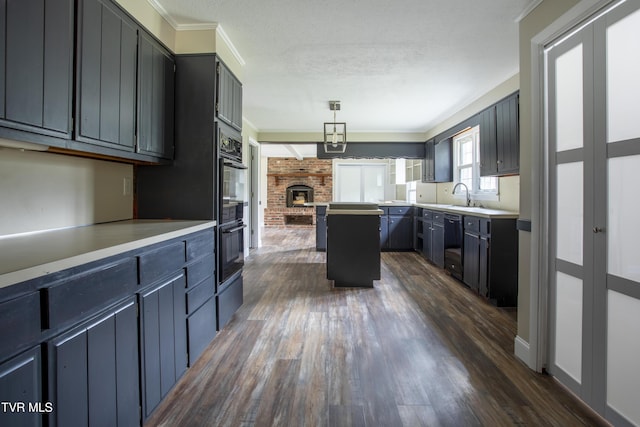 kitchen with pendant lighting, dark wood-type flooring, crown molding, a fireplace, and a textured ceiling