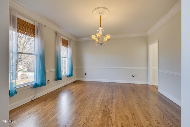 empty room featuring hardwood / wood-style floors, ornamental molding, plenty of natural light, and a notable chandelier