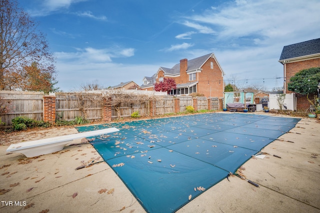 view of swimming pool featuring a diving board and a patio