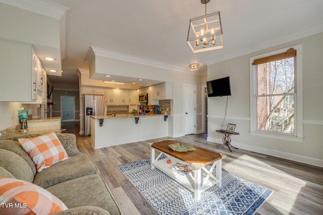 living room featuring a notable chandelier, light wood-type flooring, and crown molding