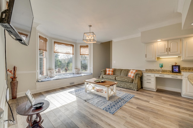 living room featuring light hardwood / wood-style floors, ornamental molding, and a notable chandelier