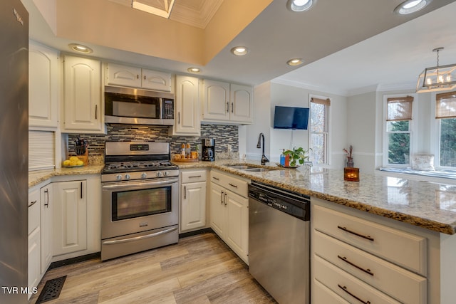 kitchen with kitchen peninsula, white cabinetry, sink, and appliances with stainless steel finishes