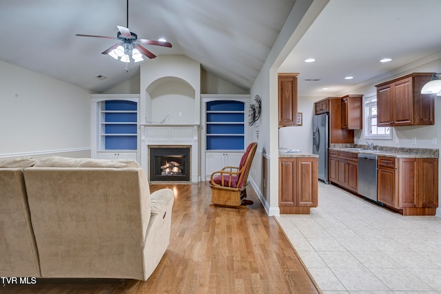 kitchen with crown molding, sink, vaulted ceiling, light hardwood / wood-style flooring, and appliances with stainless steel finishes