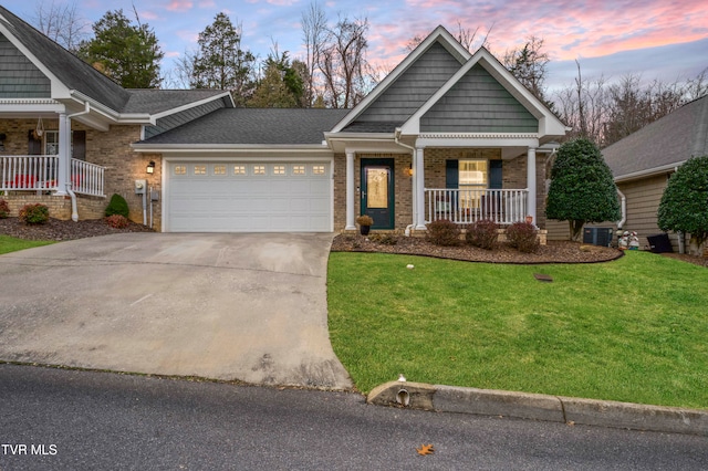 craftsman house with covered porch, a garage, and a yard