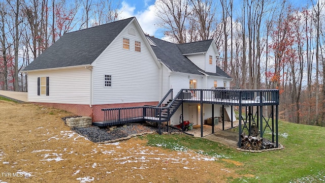 back of house featuring a lawn, a wooden deck, and a patio area