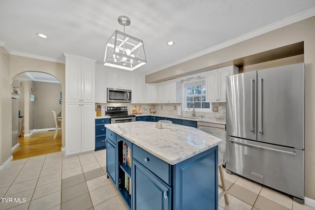 kitchen with white cabinets, appliances with stainless steel finishes, blue cabinetry, and pendant lighting