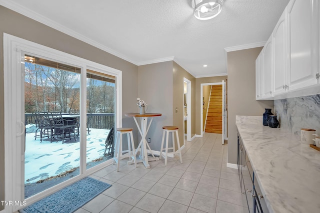 kitchen featuring light stone countertops, a textured ceiling, crown molding, light tile patterned floors, and white cabinetry