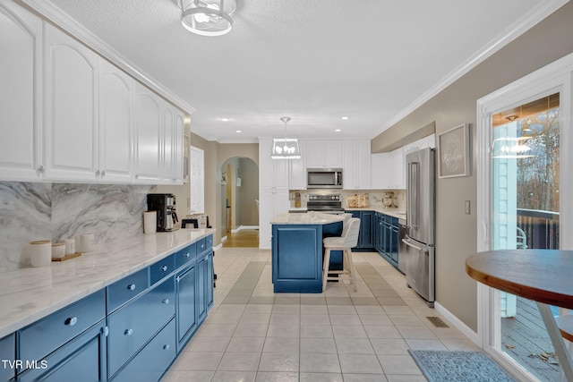 kitchen with a kitchen bar, appliances with stainless steel finishes, backsplash, blue cabinetry, and white cabinets