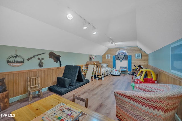 recreation room featuring wooden walls, track lighting, vaulted ceiling, and hardwood / wood-style flooring