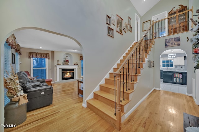 stairway featuring hardwood / wood-style floors and high vaulted ceiling