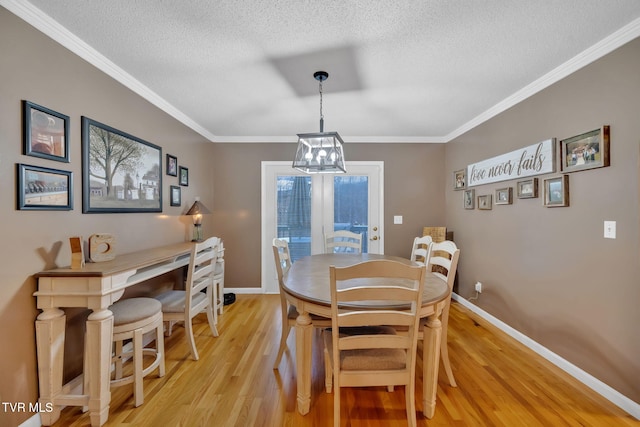 dining area with an inviting chandelier, ornamental molding, a textured ceiling, and light wood-type flooring