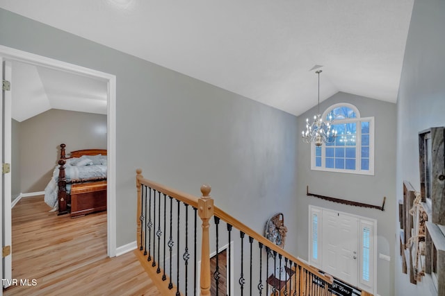 foyer entrance with an inviting chandelier, lofted ceiling, and light hardwood / wood-style flooring