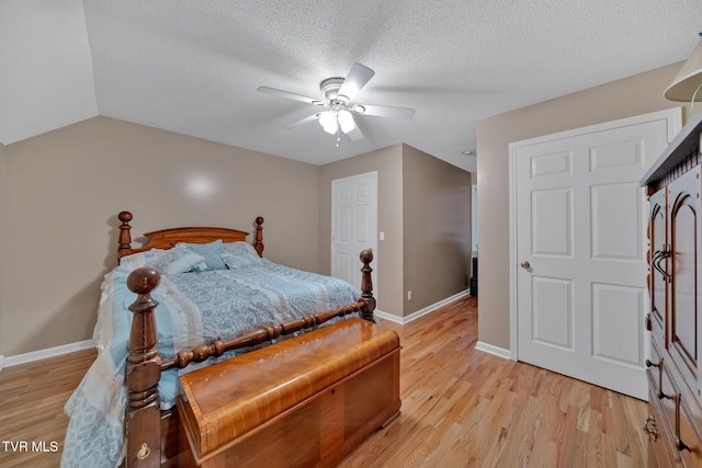 bedroom with a textured ceiling, ceiling fan, light hardwood / wood-style floors, and lofted ceiling