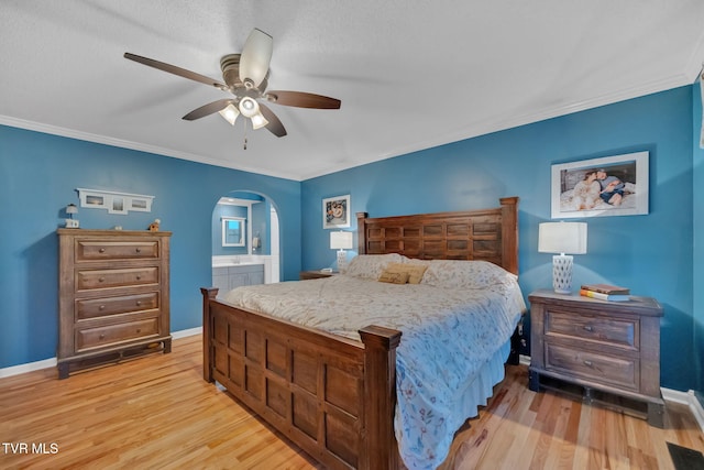 bedroom with ceiling fan, light hardwood / wood-style floors, ornamental molding, and ensuite bath