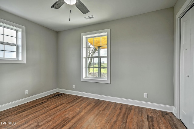 spare room featuring dark wood-type flooring, a wealth of natural light, and ceiling fan