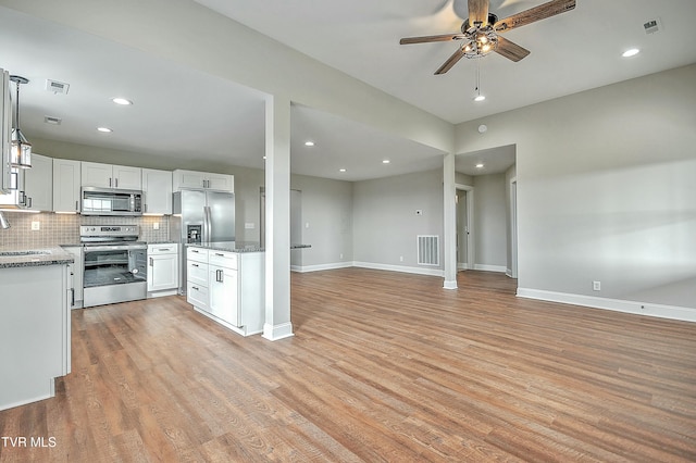 kitchen featuring white cabinetry, stainless steel appliances, light stone countertops, and hanging light fixtures