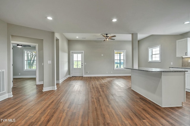 kitchen with ceiling fan, white cabinetry, backsplash, dark stone countertops, and dark hardwood / wood-style floors