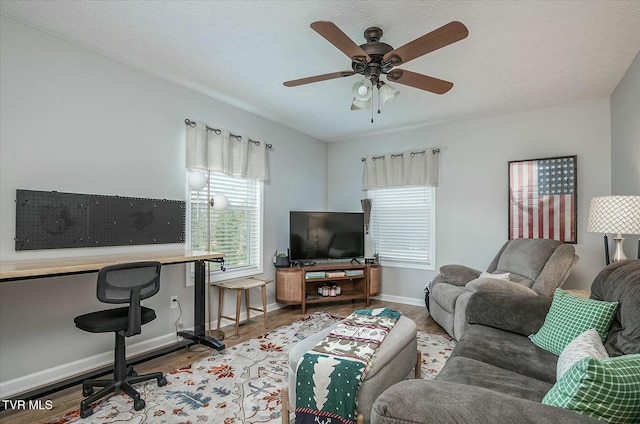 living room featuring ceiling fan, wood-type flooring, and a textured ceiling