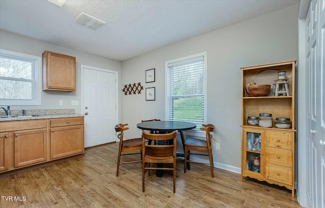 dining space with a healthy amount of sunlight, light wood-type flooring, and sink