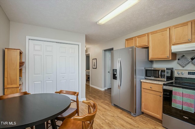 kitchen with light brown cabinets, a textured ceiling, stainless steel appliances, and light hardwood / wood-style flooring