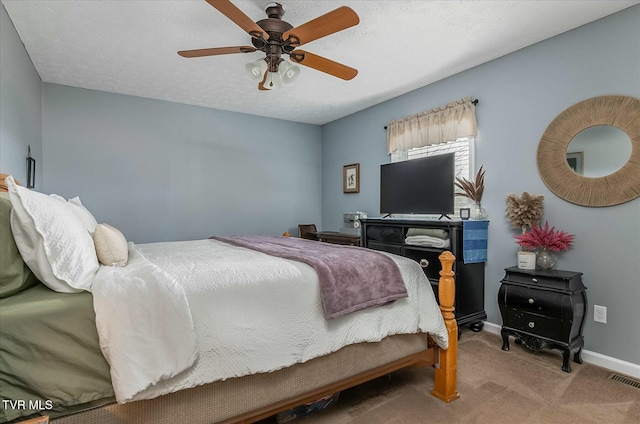 carpeted bedroom featuring ceiling fan and a textured ceiling