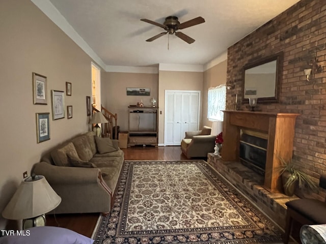 living room with dark hardwood / wood-style floors, ceiling fan, brick wall, and a brick fireplace